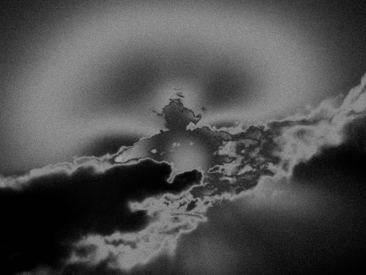 Photographie artistique en noir et blanc d’un paysage cotier désert, avec ciel nuageux et plage balayee par le vent. Style granuleux et minimaliste, evoquant la solitude, le silence et la poesie du littoral.